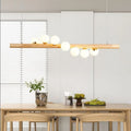 Linear wooden chandelier with seven frosted glass globes over a dining table