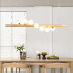 Linear wooden chandelier with seven frosted glass globes over a dining table