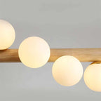 Linear wooden chandelier with seven frosted glass globes over a dining table