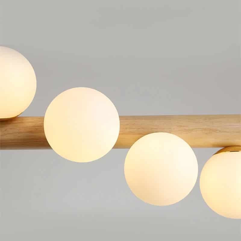 Linear wooden chandelier with seven frosted glass globes over a dining table