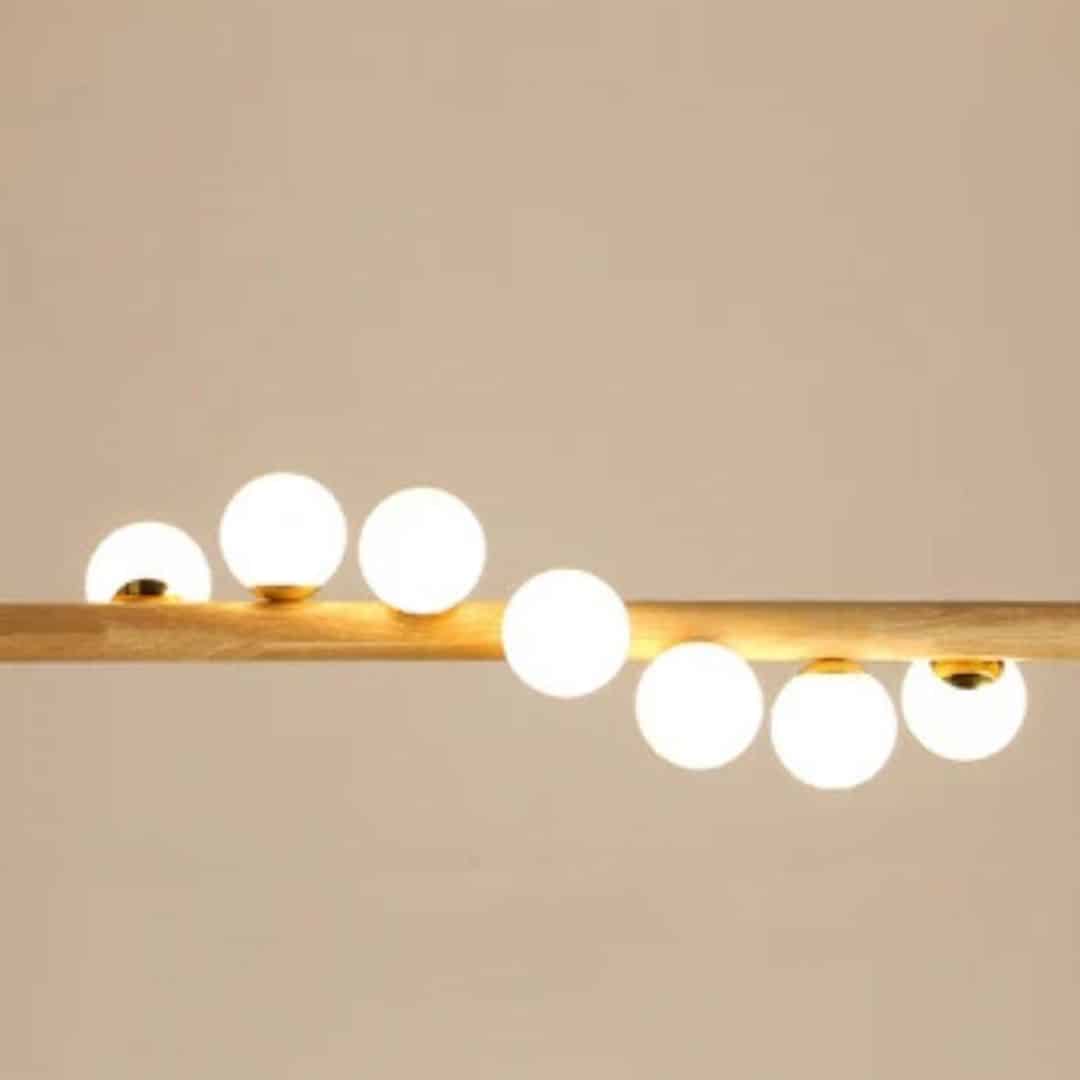 Linear wooden chandelier with seven frosted glass globes over a dining table