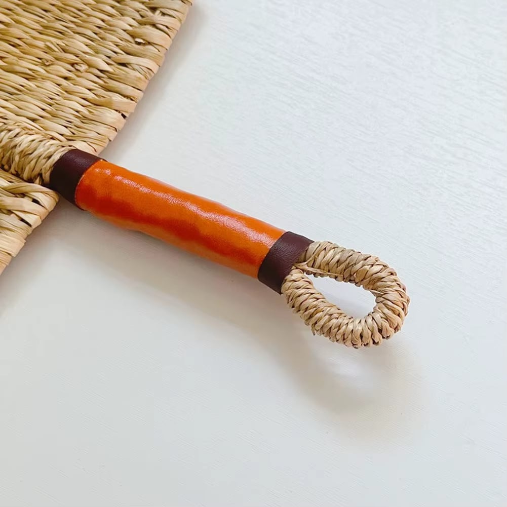 Arched woven paddle hand fan with an orange wrapped handle and loop