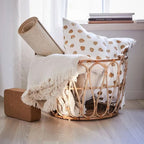 Open frame rattan basket holding folded blankets