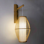 Openwork oval bamboo wall sconce hanging from a bamboo arm