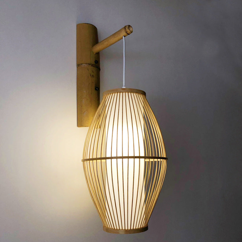 Openwork oval bamboo wall sconce hanging from a bamboo arm