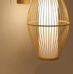 Openwork oval bamboo wall sconce hanging from a bamboo arm