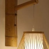 Openwork oval bamboo wall sconce hanging from a bamboo arm