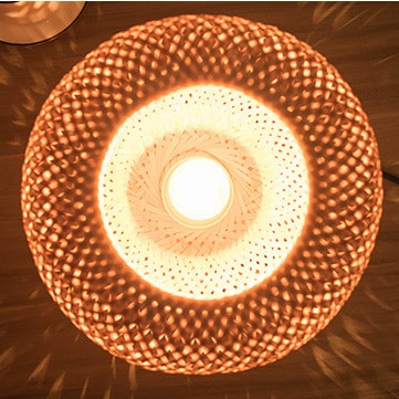 Oval bedside lamp with a hand woven rattan shade on a metal base