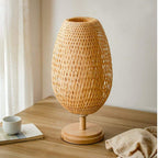 Oval bedside lamp with a hand woven rattan shade on a turned wood base
