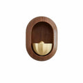 Brass bell inside an oval dark wood frame for a door
