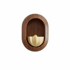 Brass bell inside an oval dark wood frame for a door