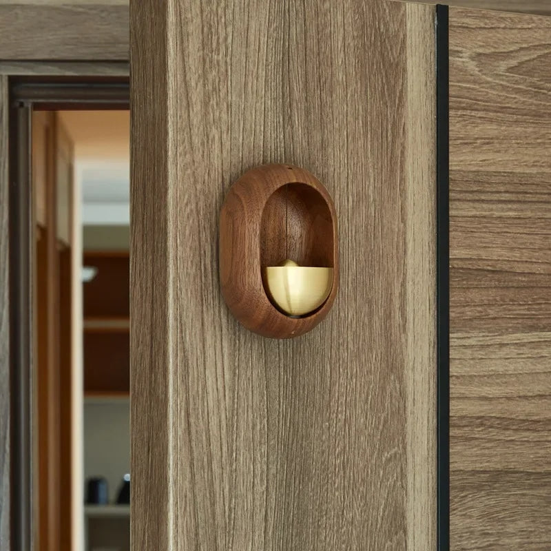 Brass bell inside an oval dark wood frame for a door