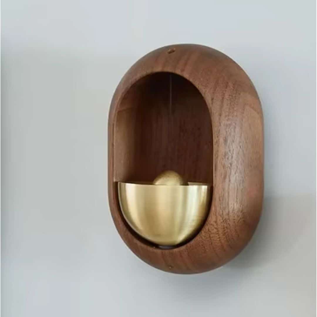 Brass bell inside an oval dark wood frame for a door