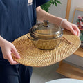 Large oval hand woven rattan serving mat under a glass casserole