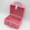 Small pink woven rattan box shaped like a retro suitcase with straps