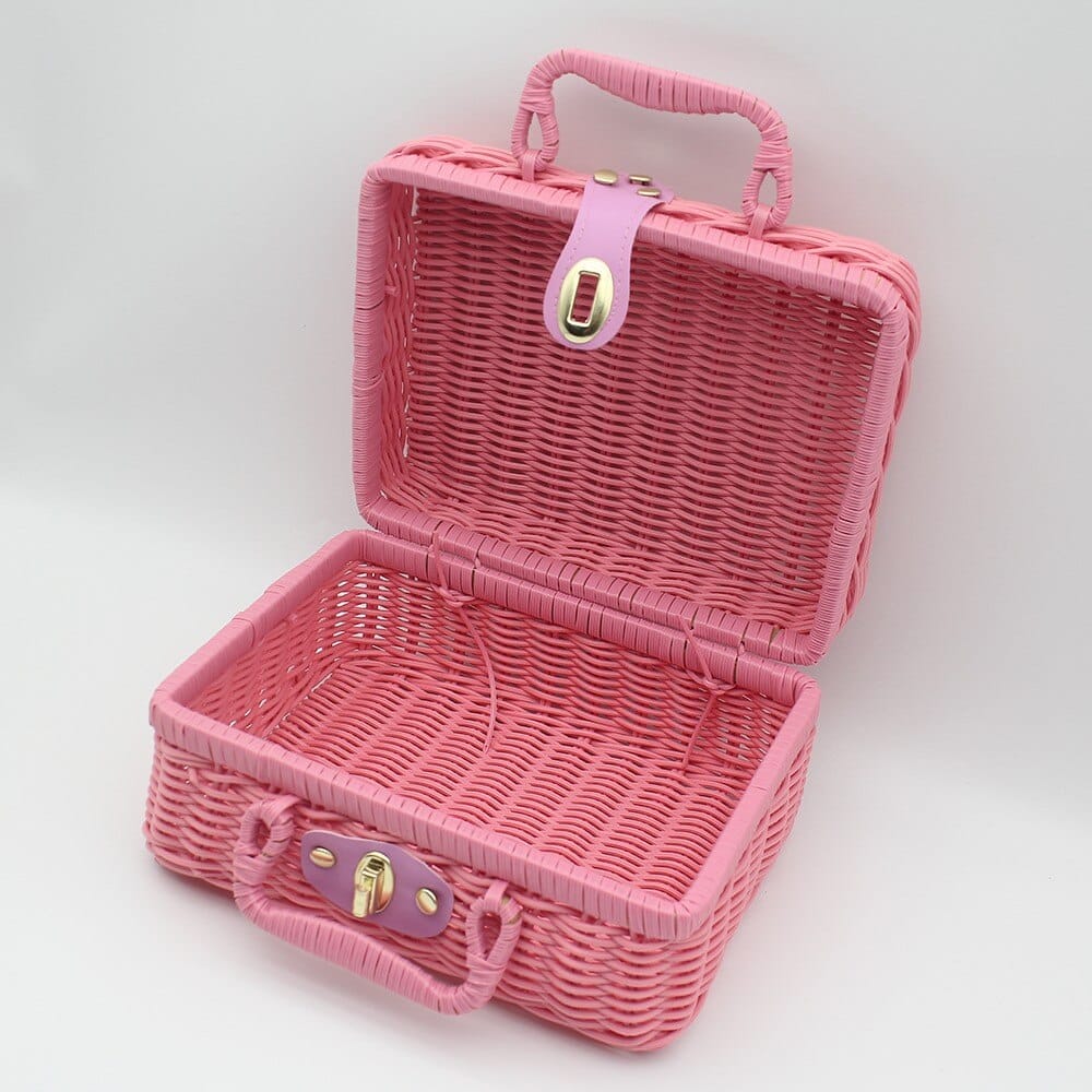 Small pink woven rattan box shaped like a retro suitcase with straps