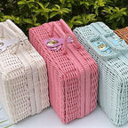 Small pink woven rattan box shaped like a retro suitcase with straps