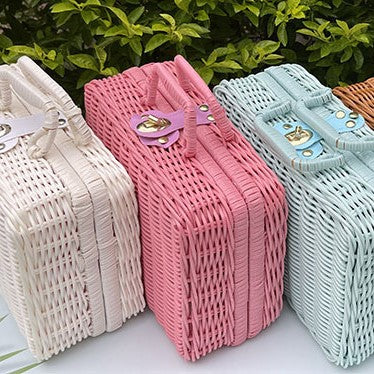 Small pink woven rattan box shaped like a retro suitcase with straps
