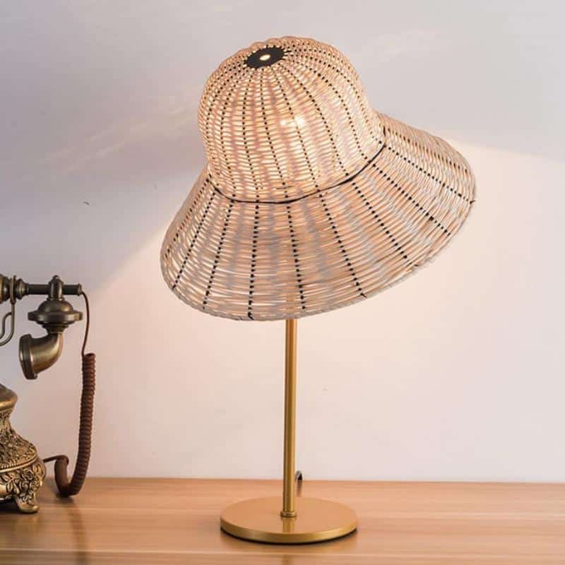 Table lamp with a wide hand woven rattan hat shaped shade and woven base