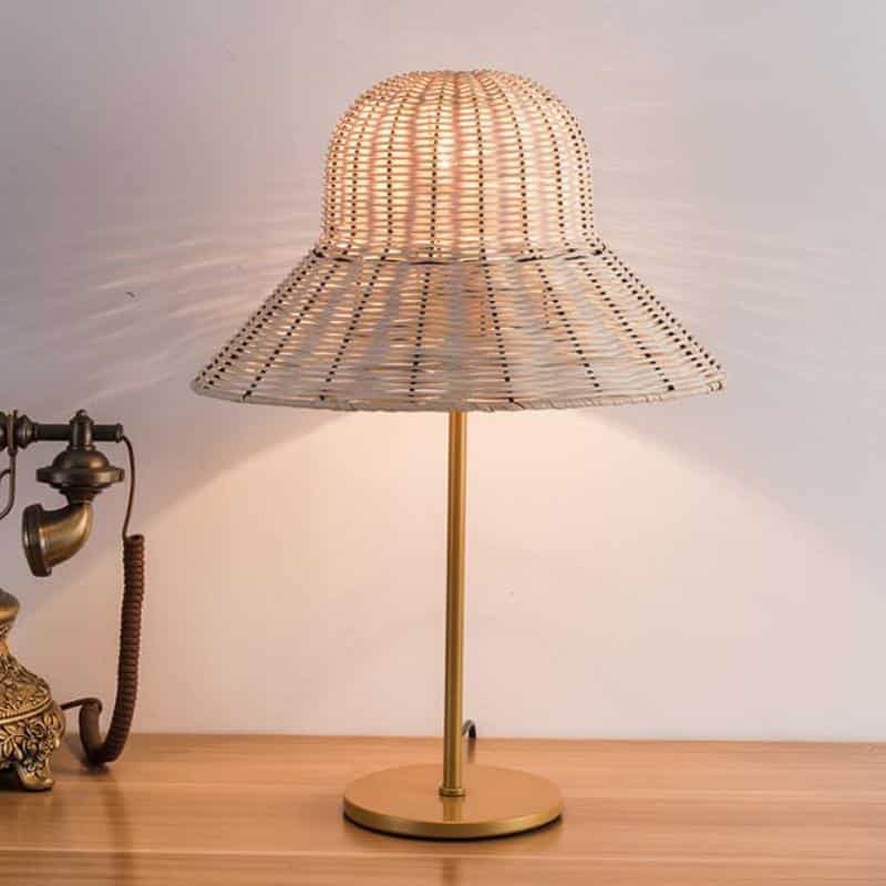 Table lamp with a wide hand woven rattan hat shaped shade and woven base