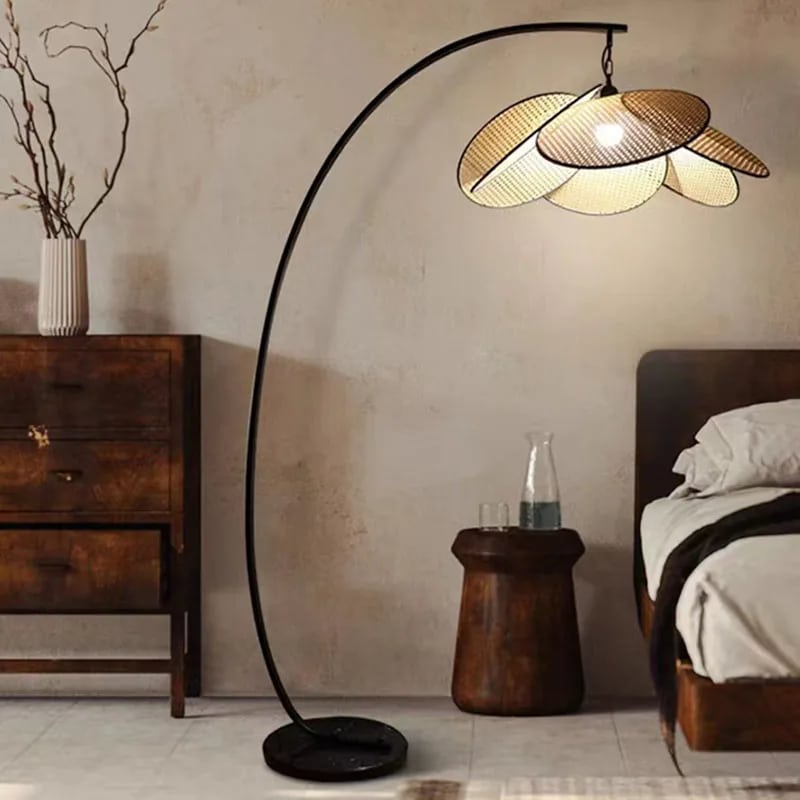 Tall floor lamp with hand woven rattan petals opening in a crown on a black stand