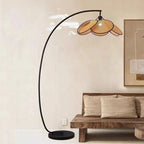 Tall floor lamp with hand woven rattan petals opening in a crown on a black stand