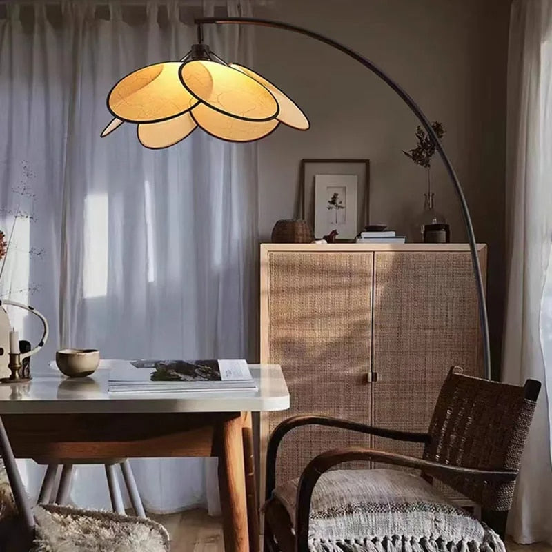 Tall floor lamp with hand woven rattan petals opening in a crown on a black stand