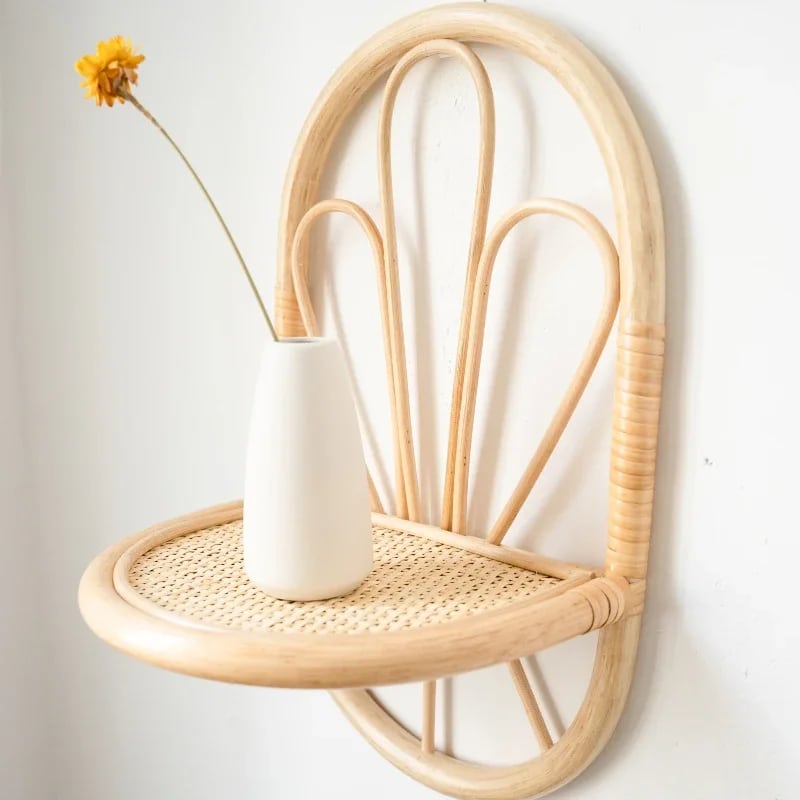 Rattan wall shelf with petal back and cane webbing ledge holding a vase