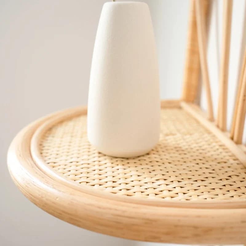 Rattan wall shelf with petal back and cane webbing ledge holding a vase