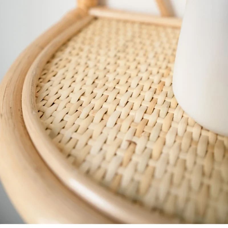 Rattan wall shelf with petal back and cane webbing ledge holding a vase