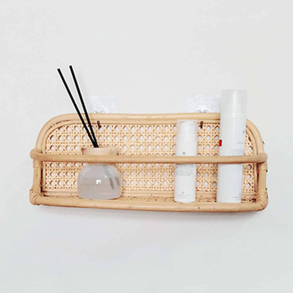 Hand woven rattan wall rack with metal coat hooks in a warm beige