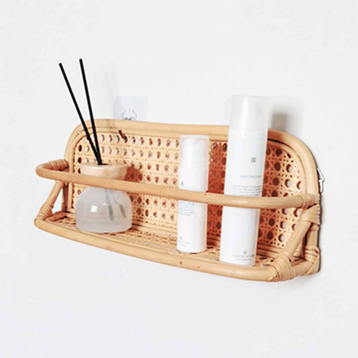 Hand woven rattan wall rack with metal coat hooks in a warm beige