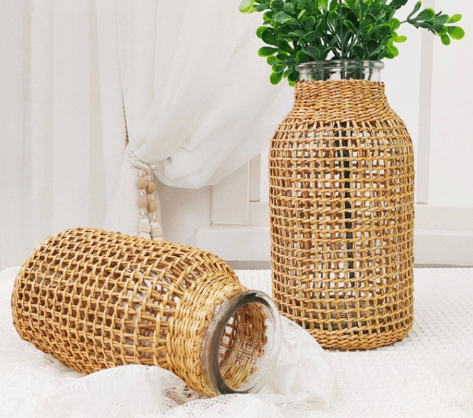 Glass bottle vase wrapped in woven rattan holding poppies