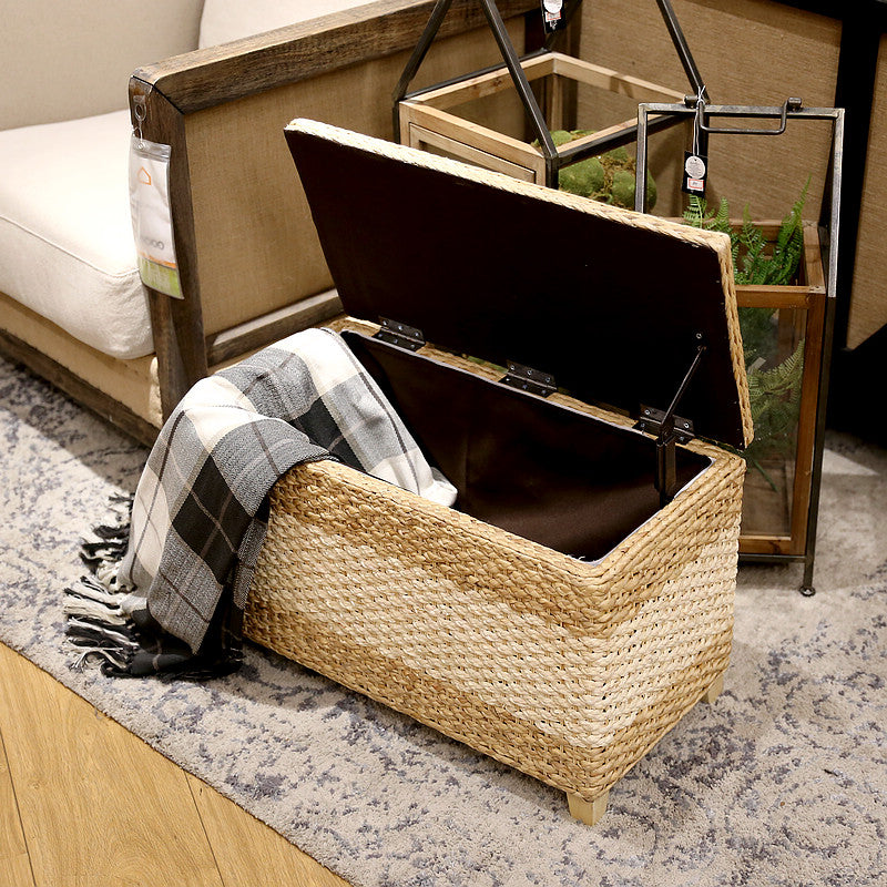 Rectangular hand woven rattan storage stool with a lift off lid on wood feet