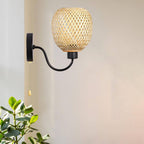 Retro wall sconce with a hand woven bamboo shade on a curved black iron arm