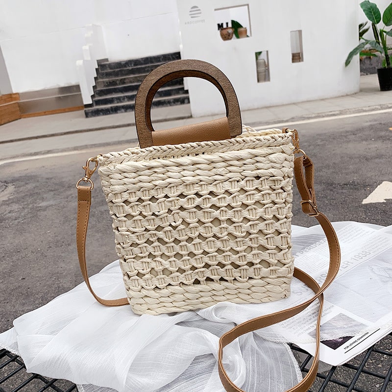Rounded retro woven straw bag with a varnished wooden handle and shoulder strap