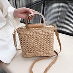 Rounded retro woven straw bag with a varnished wooden handle and shoulder strap