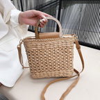 Rounded retro woven straw bag with a varnished wooden handle and shoulder strap