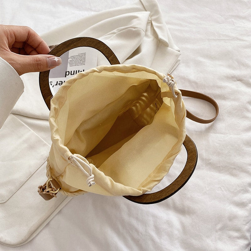 Rounded retro woven straw bag with a varnished wooden handle and shoulder strap
