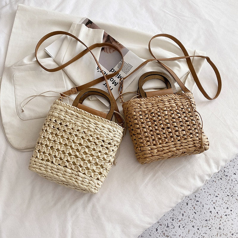 Rounded retro woven straw bag with a varnished wooden handle and shoulder strap