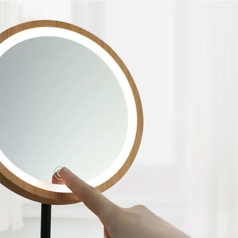 Round LED makeup mirror with 3x magnifier on a wood base