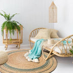 Round braided natural rug with a teal ring and thin dark stripes