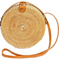 Round structured brown rattan crossbody bag with an adjustable shoulder strap