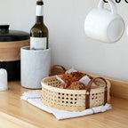 Round low cane webbing basket with leather handles in beige