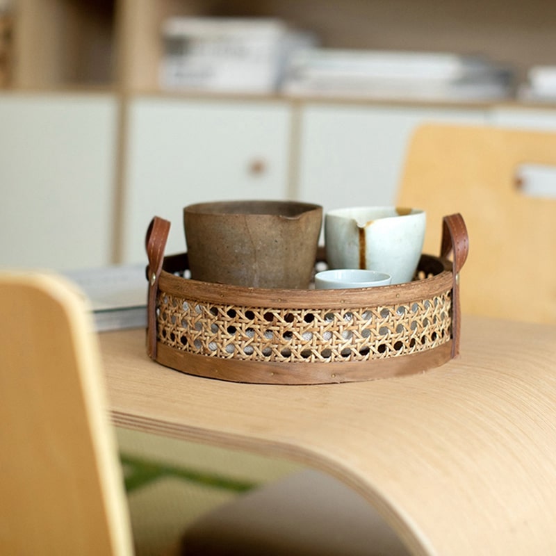 Round low cane webbing basket with leather handles in brown