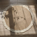 Round woven cotton and linen rug with a cream fringe
