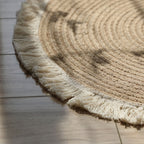 Round woven cotton and linen rug with a cream fringe