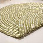 Round sage green and cream braided rug in a bright room