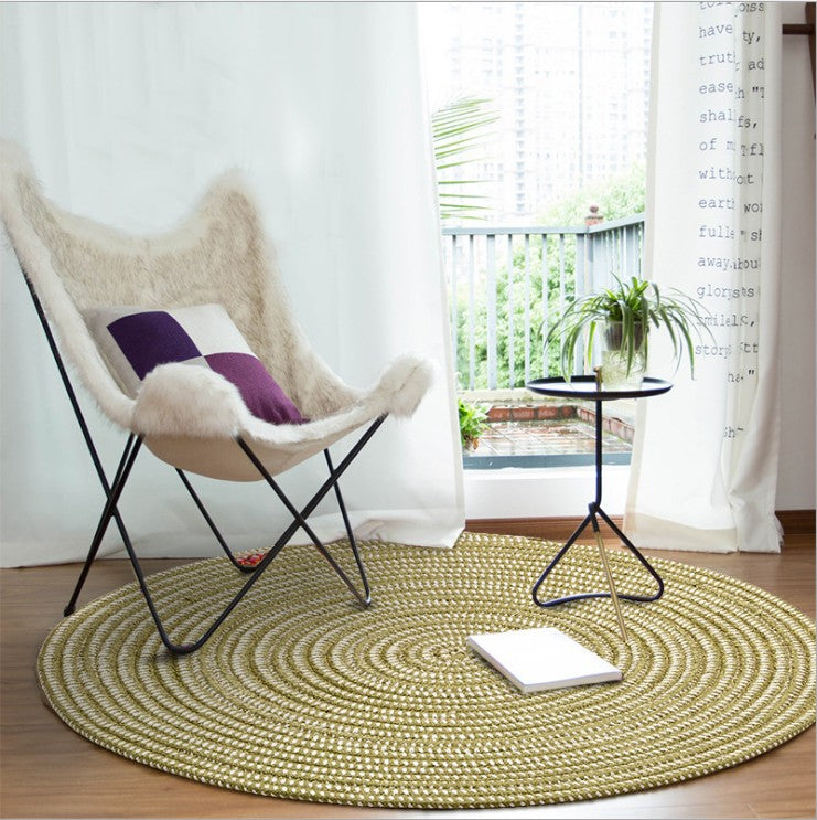 Round sage green and cream braided rug in a bright room