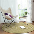Round sage green and cream braided rug in a bright room